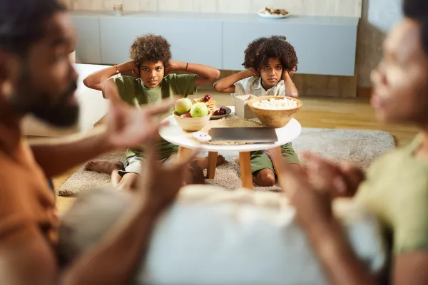 Children covering their ears while their parents argue